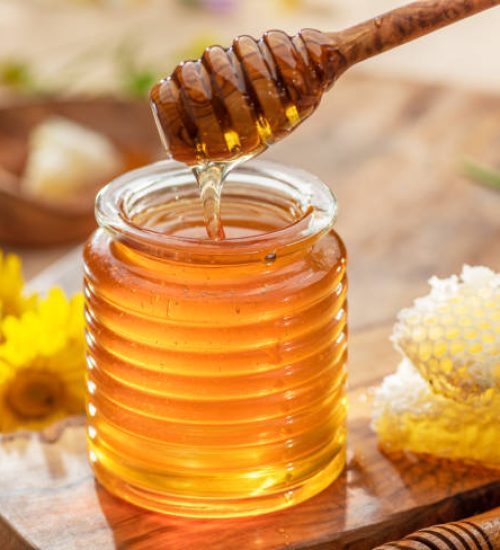 Natural organic honey in glass jar, honey dipper and honeycombs are near. Natural food background.